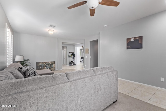 living area featuring light tile patterned floors, visible vents, baseboards, and ceiling fan