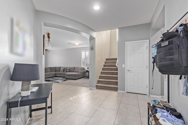 entryway with light tile patterned floors, baseboards, and stairs