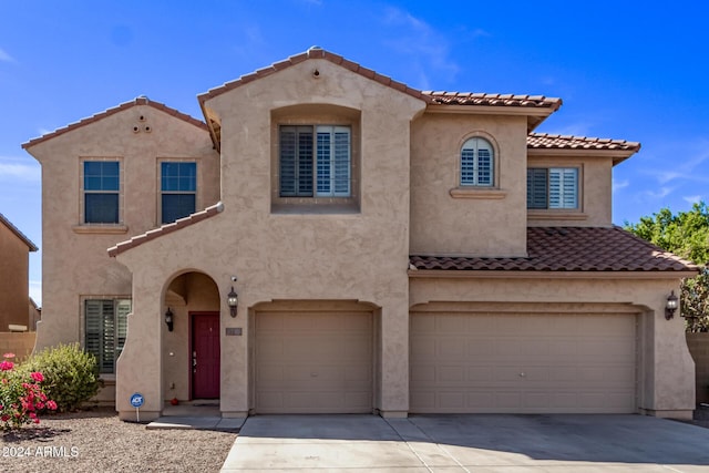 mediterranean / spanish-style house with stucco siding, a tiled roof, concrete driveway, and a garage