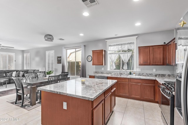 kitchen with visible vents, a sink, stainless steel appliances, open floor plan, and a center island