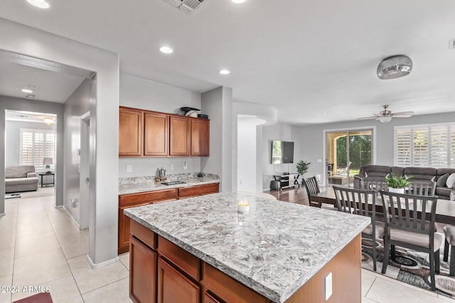 kitchen featuring visible vents, a kitchen island, open floor plan, a wealth of natural light, and brown cabinetry