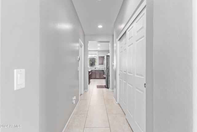 hallway featuring light tile patterned floors, baseboards, and recessed lighting