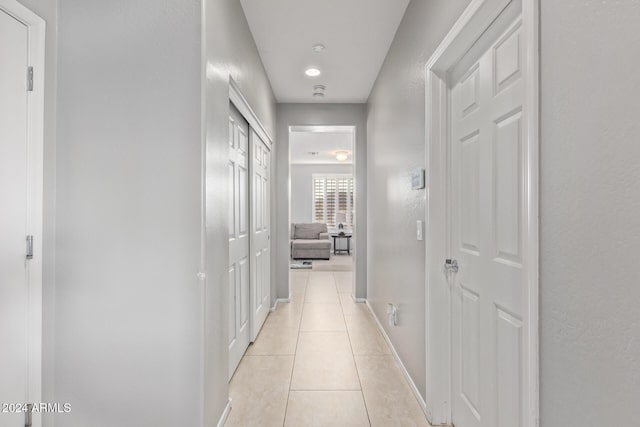 corridor featuring light tile patterned floors and baseboards