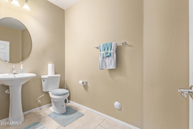 bathroom with tile patterned floors, baseboards, toilet, and a sink