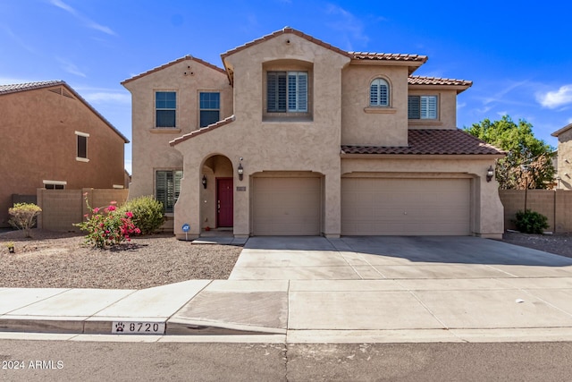 mediterranean / spanish home featuring fence, concrete driveway, a tile roof, stucco siding, and a garage