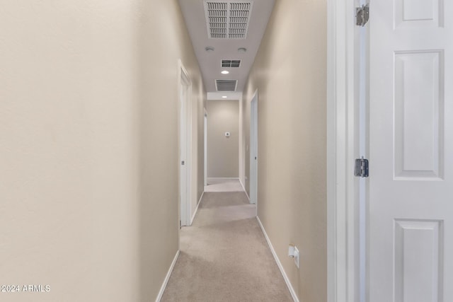 corridor with light carpet, visible vents, and baseboards