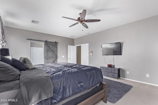 carpeted bedroom featuring a barn door, baseboards, visible vents, and ceiling fan