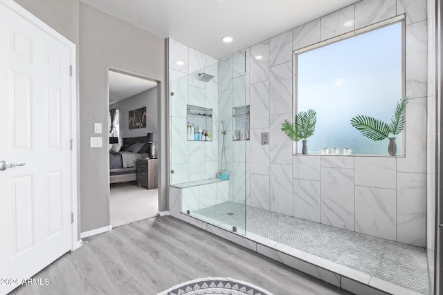 full bath featuring wood finished floors, recessed lighting, connected bathroom, a marble finish shower, and baseboards