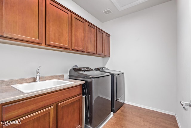 laundry room featuring visible vents, light wood finished floors, cabinet space, a sink, and washing machine and dryer