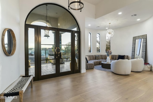 interior space with french doors, an inviting chandelier, and light hardwood / wood-style flooring