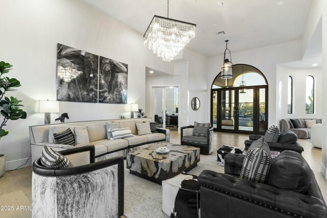 living room with light wood-type flooring, french doors, and a notable chandelier