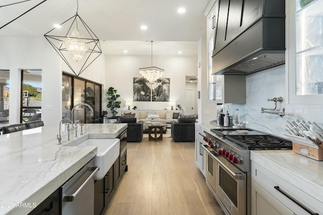 kitchen featuring light stone countertops, hanging light fixtures, appliances with stainless steel finishes, and premium range hood