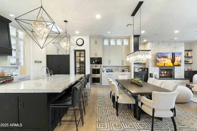 kitchen with built in fridge, white cabinets, decorative light fixtures, a large island, and light stone counters