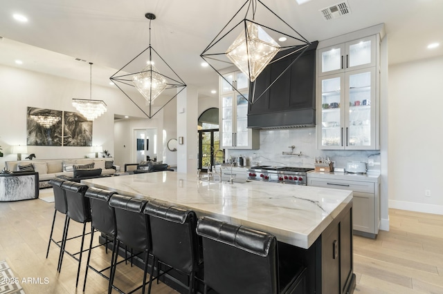 kitchen featuring light stone countertops, sink, pendant lighting, and a large island