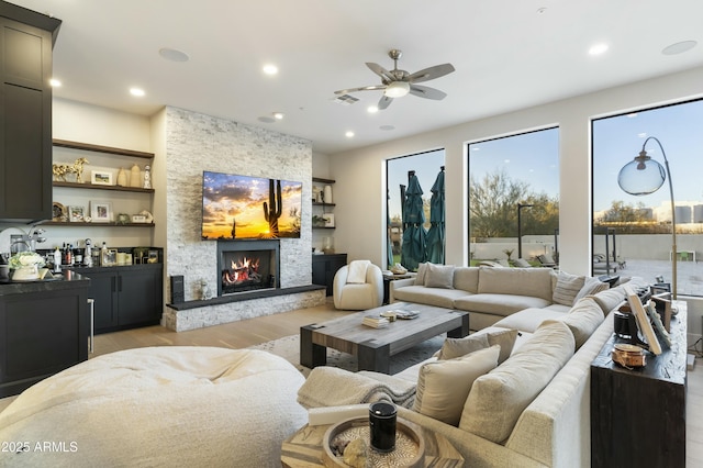 living room with ceiling fan, a fireplace, and light hardwood / wood-style floors