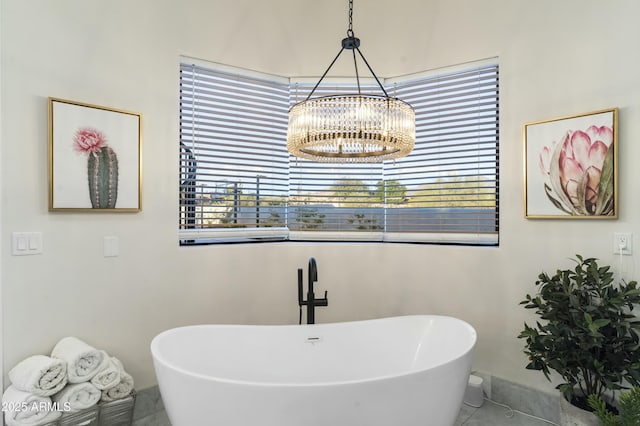 bathroom with an inviting chandelier, tile patterned flooring, and a washtub