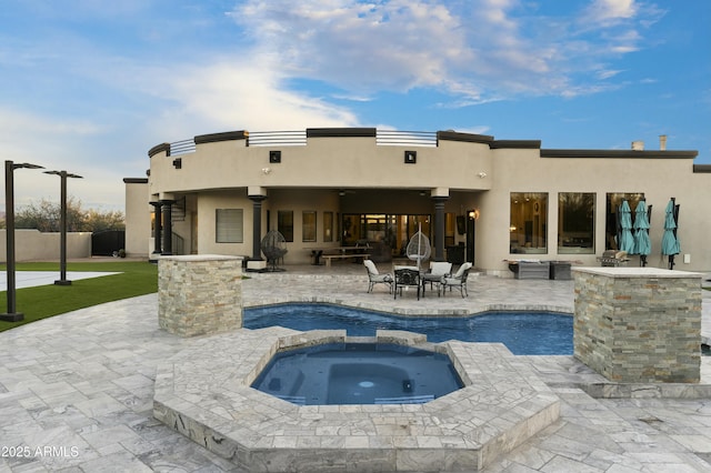 rear view of property featuring a patio area and a swimming pool with hot tub