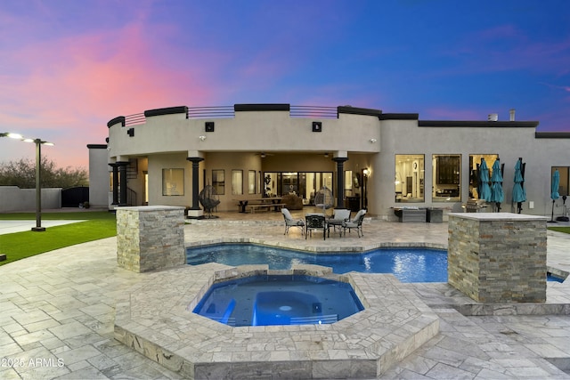 back house at dusk with a pool with hot tub, a patio area, an outdoor fire pit, and ceiling fan