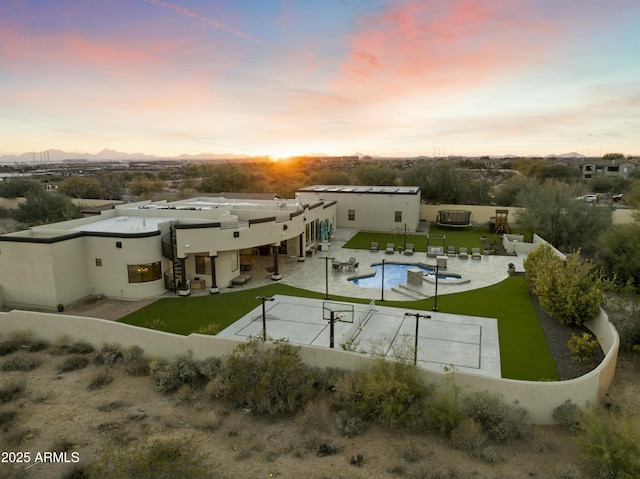 back house at dusk featuring a fenced in pool, a lawn, and a patio