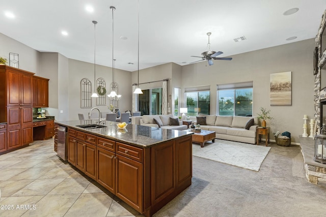 kitchen with visible vents, hanging light fixtures, a kitchen island with sink, a sink, and dishwasher