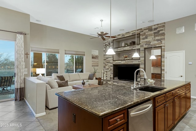 kitchen featuring ceiling fan, a sink, open floor plan, stainless steel dishwasher, and dark stone countertops