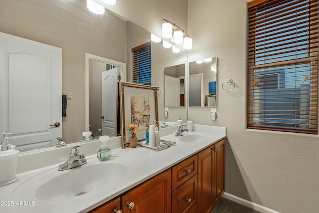 bathroom featuring double vanity, toilet, a sink, and a textured wall