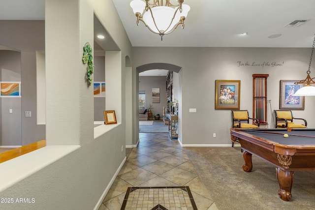 rec room with light tile patterned floors, visible vents, arched walkways, baseboards, and light colored carpet