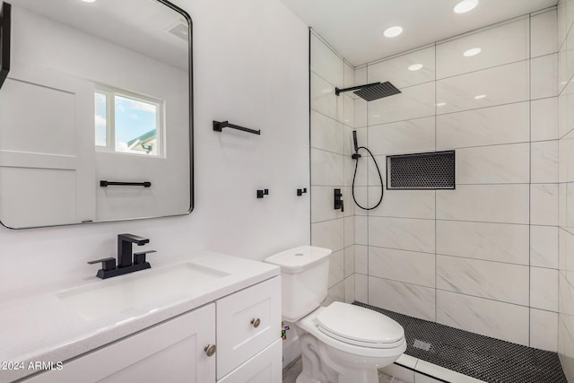 bathroom featuring tiled shower, vanity, and toilet