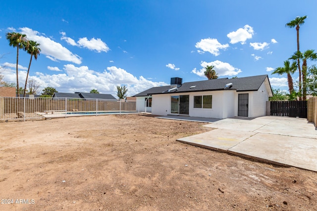 back of property featuring a patio, central air condition unit, and a fenced in pool