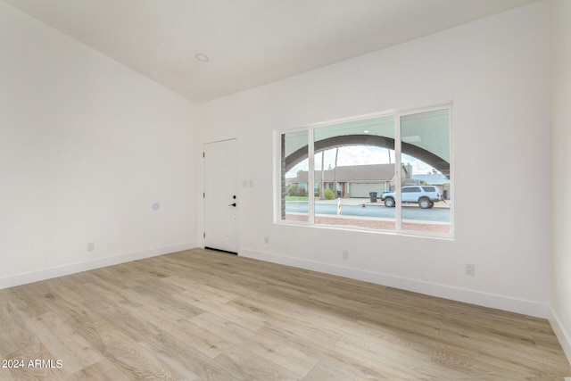 spare room with light hardwood / wood-style floors and vaulted ceiling