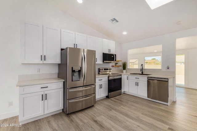 kitchen with lofted ceiling, sink, white cabinetry, appliances with stainless steel finishes, and light wood-type flooring