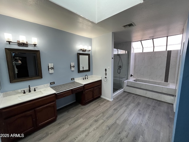 bathroom with hardwood / wood-style flooring, plus walk in shower, vanity, and a textured ceiling