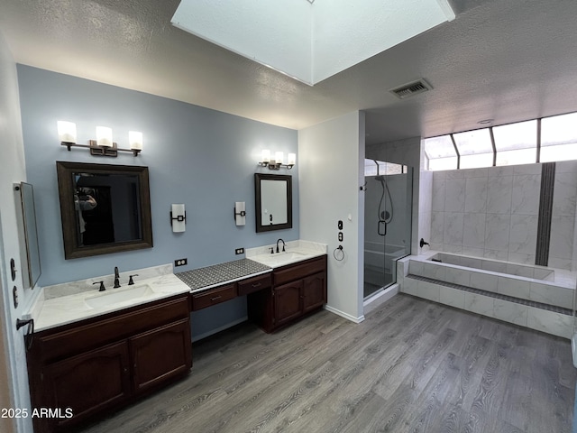 bathroom with shower with separate bathtub, hardwood / wood-style floors, vanity, and a textured ceiling