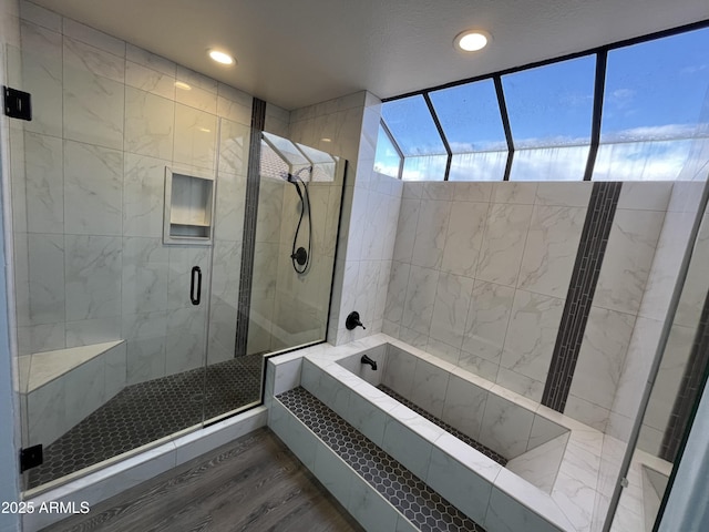 bathroom with wood-type flooring and shower with separate bathtub