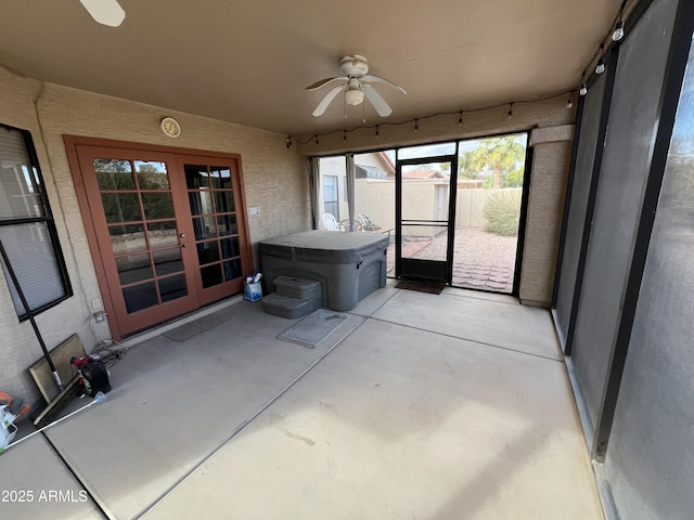 unfurnished sunroom featuring ceiling fan and french doors