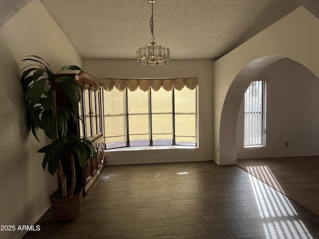 spare room featuring a notable chandelier, a textured ceiling, and dark hardwood / wood-style flooring