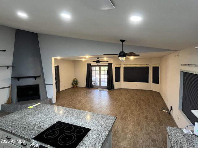 living room with dark wood-type flooring, french doors, vaulted ceiling, ceiling fan, and a fireplace