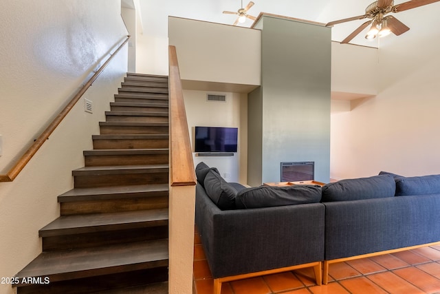 stairs with a high ceiling, tile patterned floors, and ceiling fan