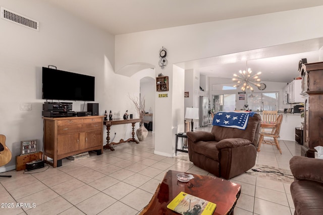 living room with lofted ceiling, a notable chandelier, and light tile patterned floors