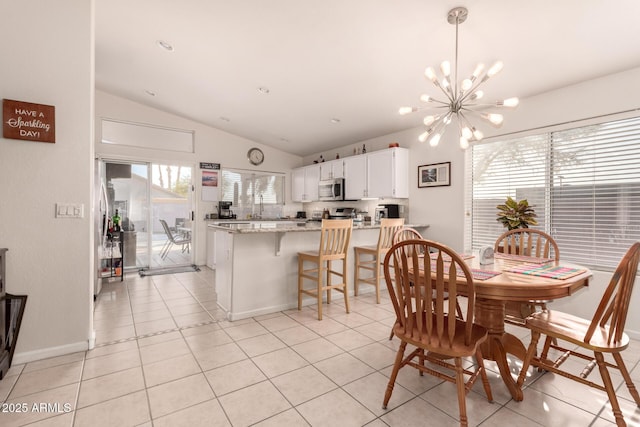 tiled dining space featuring vaulted ceiling and an inviting chandelier