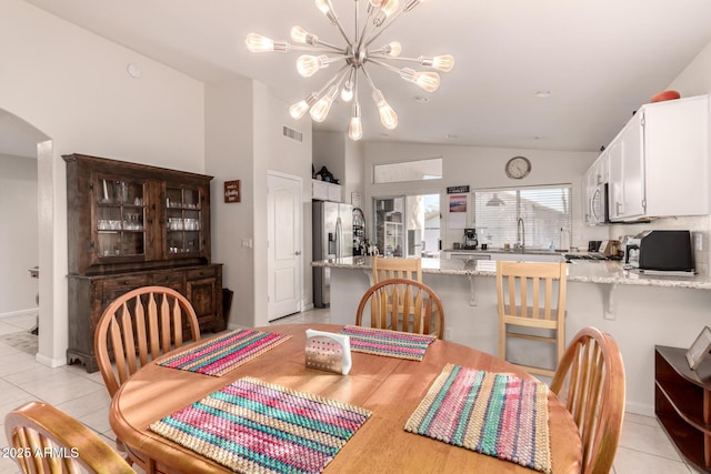 dining space featuring light tile patterned flooring, lofted ceiling, sink, and a notable chandelier