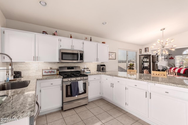 kitchen featuring sink, white cabinetry, light stone counters, appliances with stainless steel finishes, and kitchen peninsula