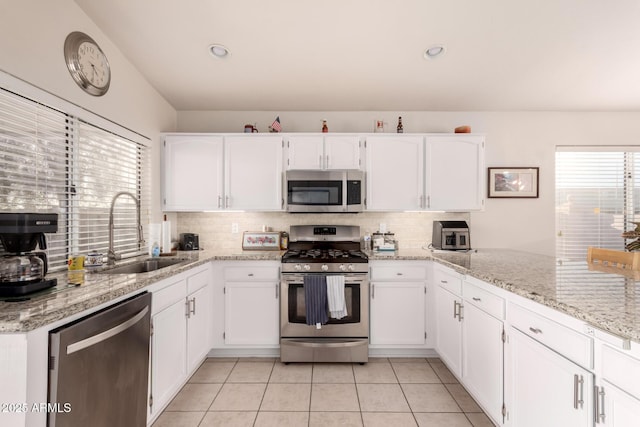 kitchen featuring stainless steel appliances, sink, white cabinets, and backsplash