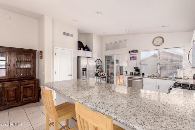 kitchen with sink, a kitchen breakfast bar, light stone countertops, and appliances with stainless steel finishes