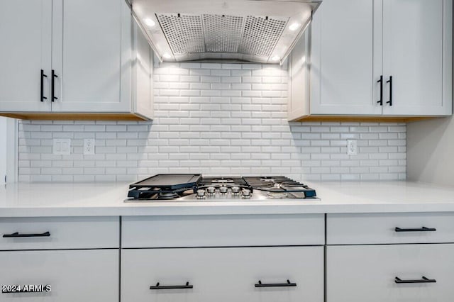 kitchen with tasteful backsplash, white cabinetry, stainless steel gas cooktop, and wall chimney range hood