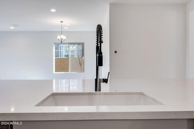 interior details featuring a chandelier, sink, hanging light fixtures, and light stone counters