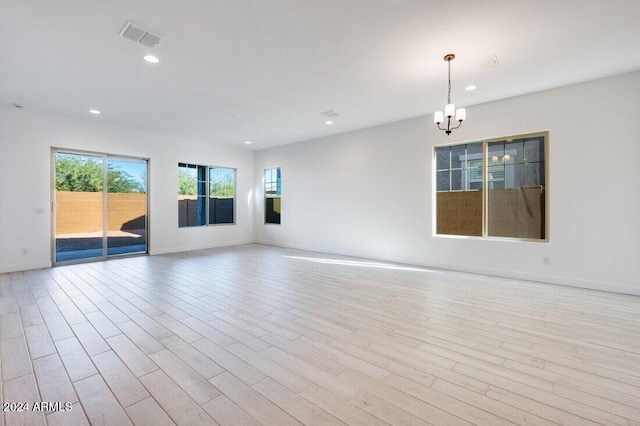 spare room with a notable chandelier and light hardwood / wood-style floors