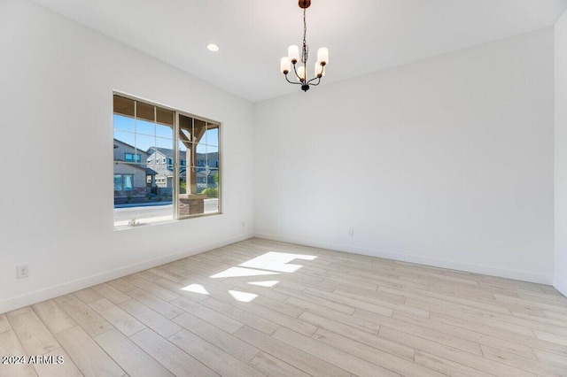 empty room with a notable chandelier and light hardwood / wood-style flooring