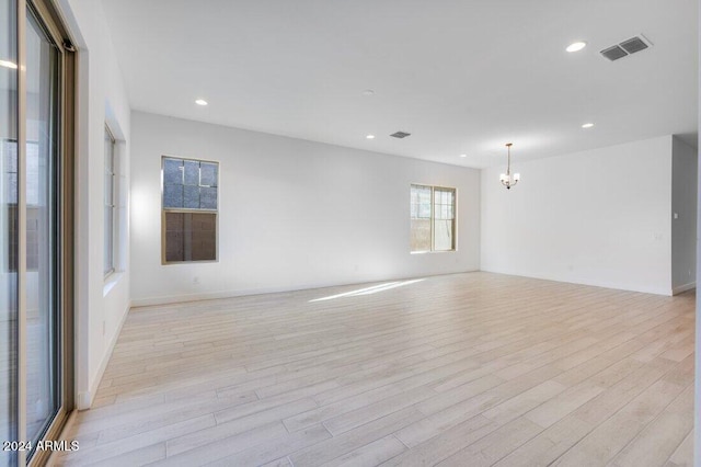 empty room with a notable chandelier and light wood-type flooring