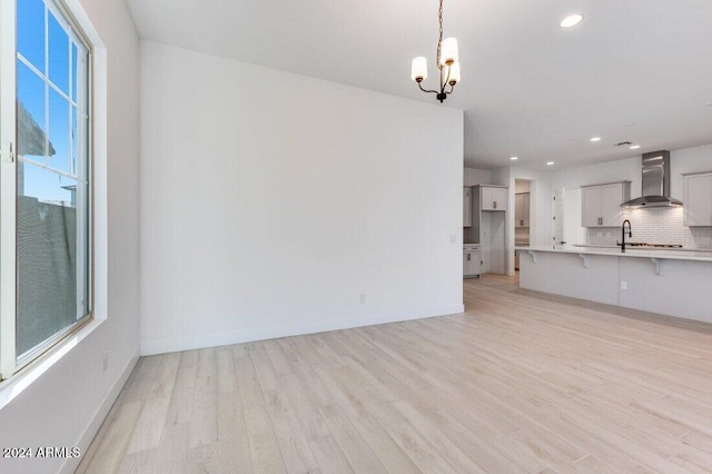 unfurnished living room with a chandelier, plenty of natural light, light hardwood / wood-style floors, and sink